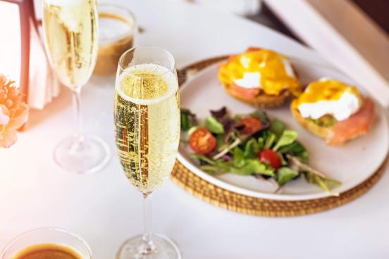 Champagne glass and brunch plates of food 