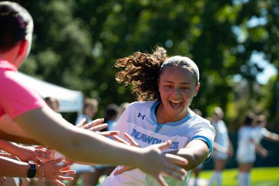 Women's soccer playing high fiving players with excitement on her face