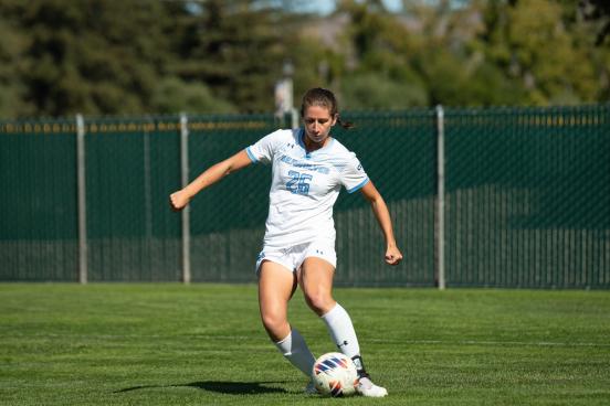 Women's soccer playing kicking a soccer ball