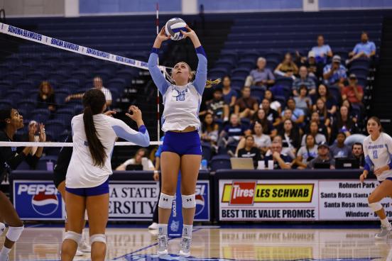 Volleyball player with hands in the air hitting volleyball