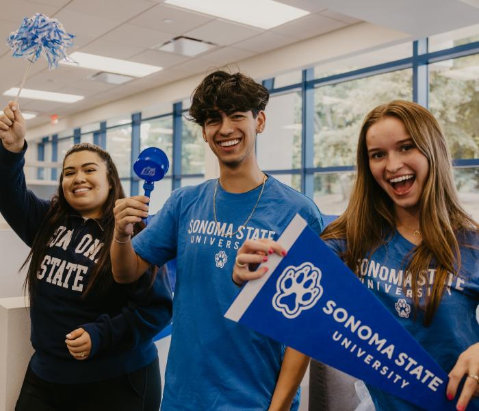 Three students cheering and holding SSU flag