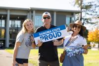 Two parents and a student holding a Sonoma State Proud banner