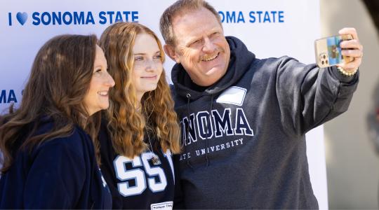 Parents and student taking a selfie photo with a phone