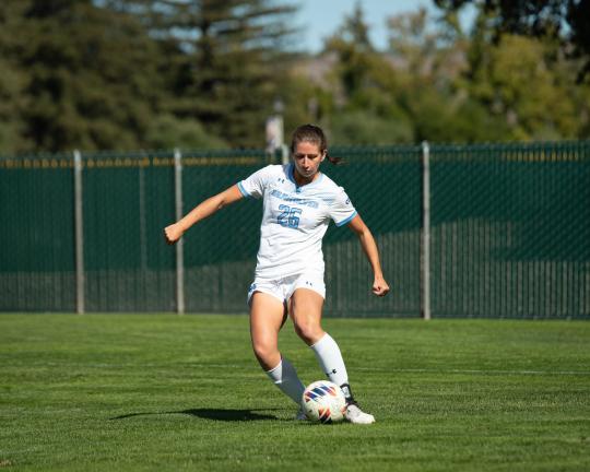 Women's soccer playing kicking a soccer ball