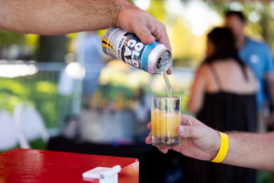 Can of Old Caz pouring beer on a alumni cup