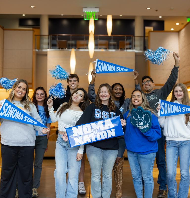 Group of students holding SSU spirit signs including SSU pennants and Proud Sonoma State signs