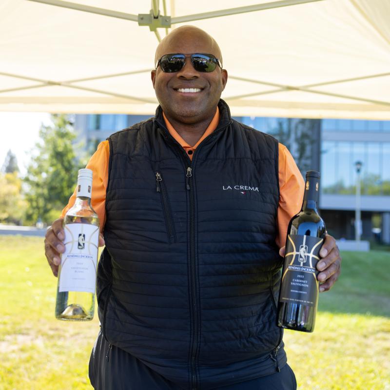 Person holding up two bottles of wine and smiling