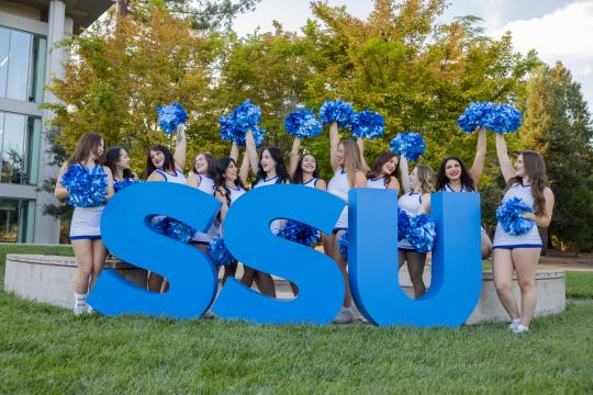 SSU large letters with group of cheerleaders with pom poms in air