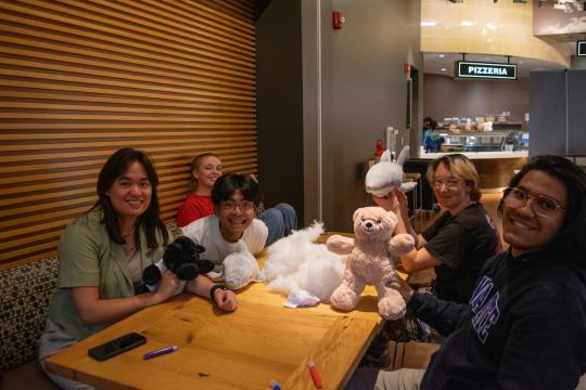 Five students holding up their stuffed animals from a build a bear night